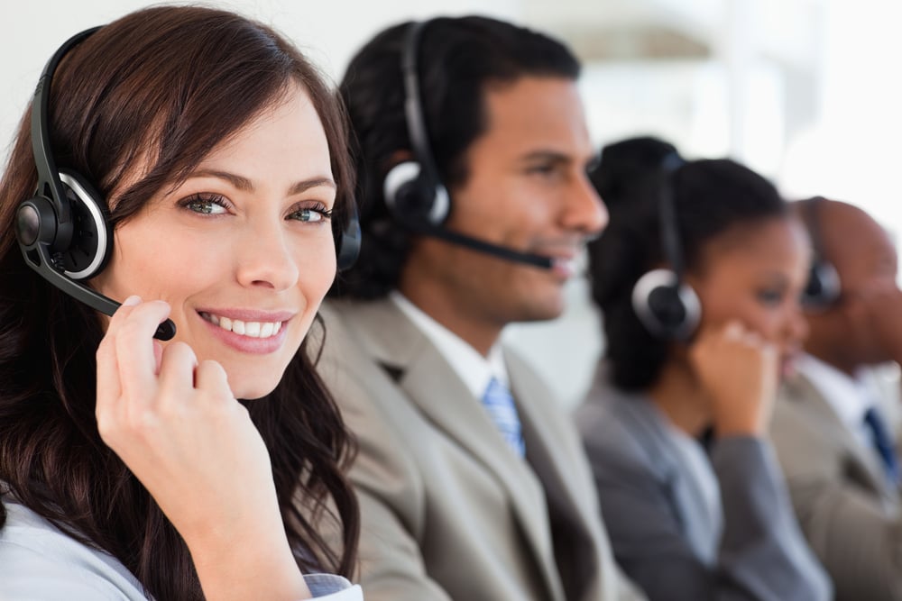 Smiling worker doing her job with a headset while looking at the camera Smiling worker doing her job with a headset while looking at the camera